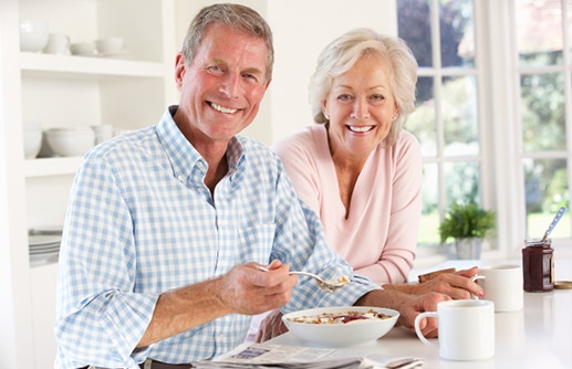 Smiling older couple having cereal and coffee at a table