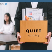 A man carrying a box full of desk materials with the words Quiet Quitting written on the box.